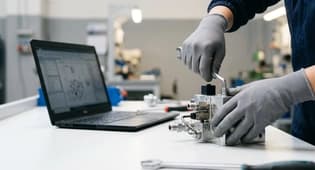Tecnico assembla una valvola oleodinamica al banco di lavoro
